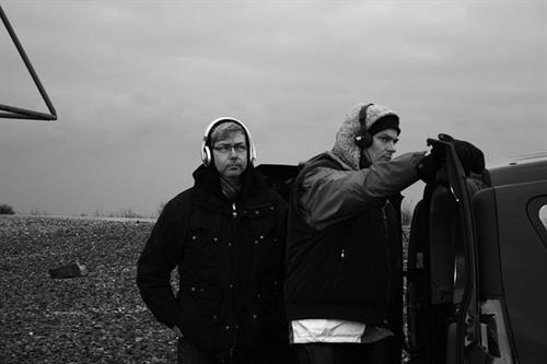 Martin De Mattia und Marc Weis von der Künstlergruppe M+M Kopfhörer tragend draussen.