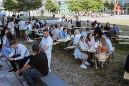 Outdoor area of the celebration. People enjoy food, drink and the beautiful weather.