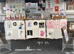 A booth with art prints by Lucky Cat Studio.